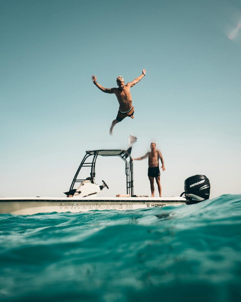 Two men enjoy a sunny adventure, jumping into the Abu Dhabi sea from a boat.